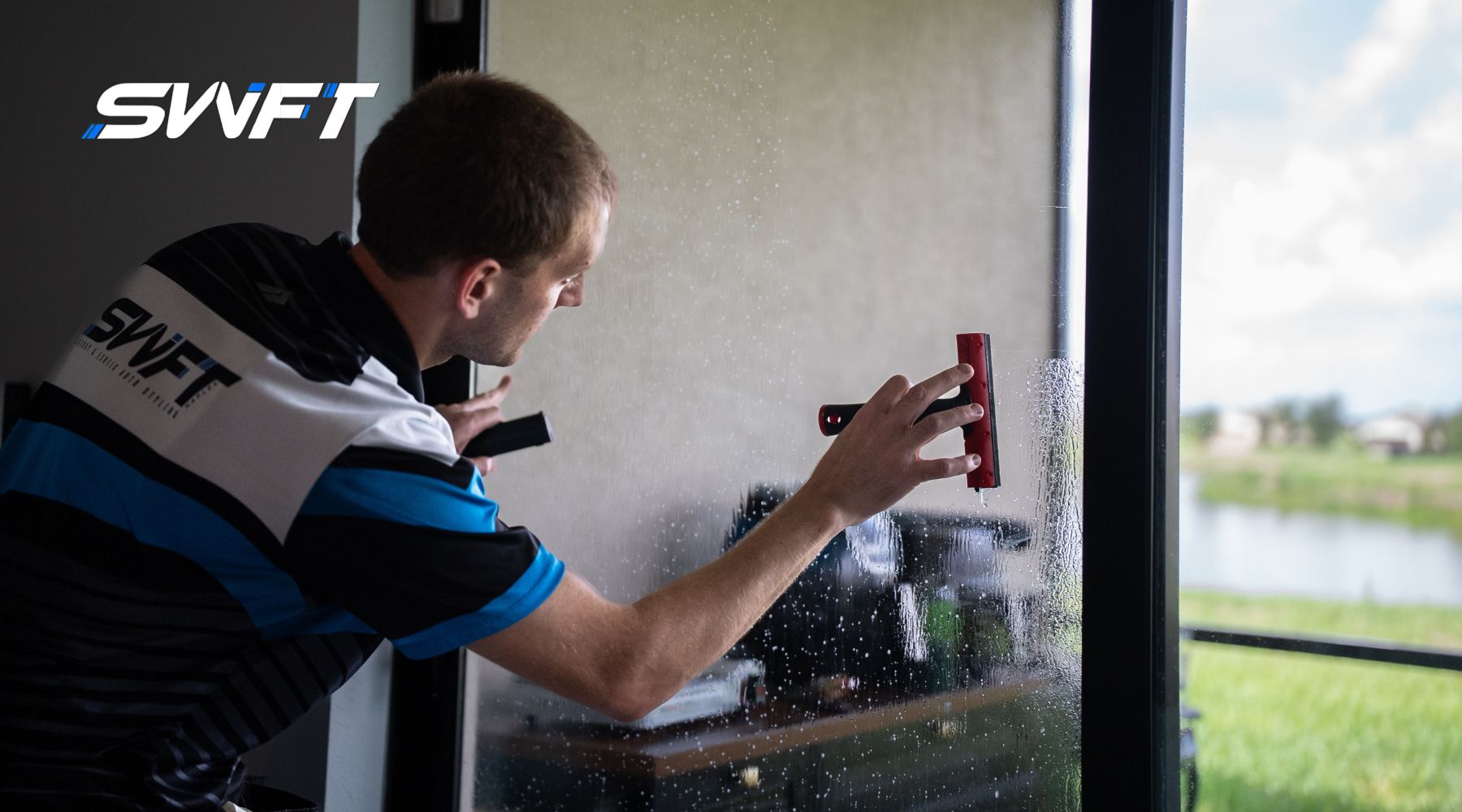 A professional window tinter installs protective film on a glass door in a Fort Myers home, highlighting the benefits of home window tinting for storm safety and security. The reflection shows a peaceful outdoor view, contrasting with the protective purpose of the film.