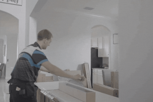 A window tinting technician in a Fort Myers home unrolls a sheet of protective window film on a kitchen counter, preparing for installation. This process is part of understanding home window tinting as both a safety measure and energy-efficient upgrade.